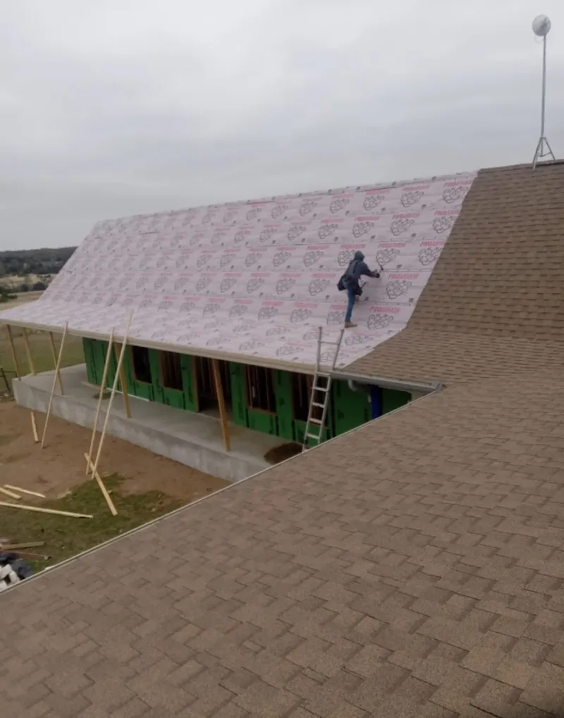 Worker preparing underlayment for a metal roof installation in Kenmore